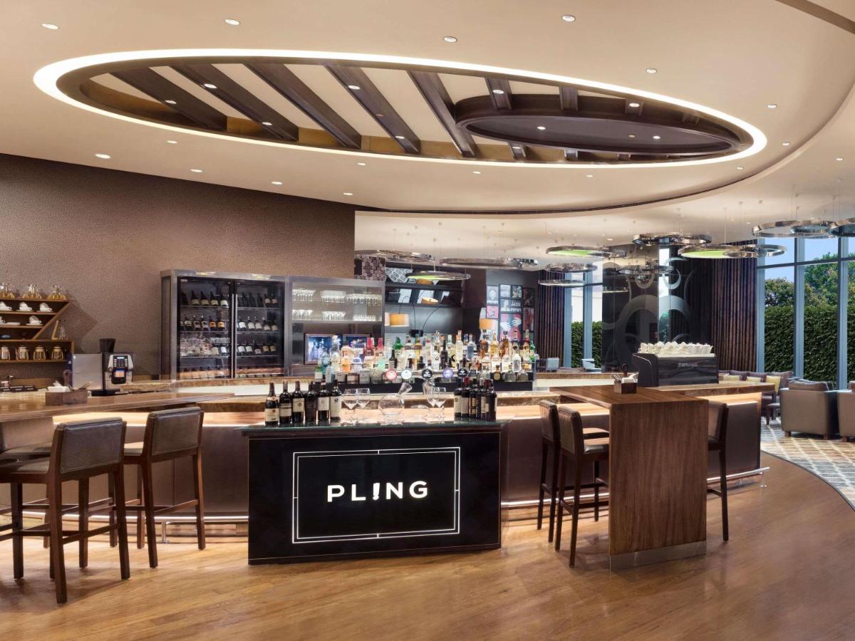 a bar in a restaurant with chairs and a bar counter at Pullman New Delhi Aerocity in New Delhi