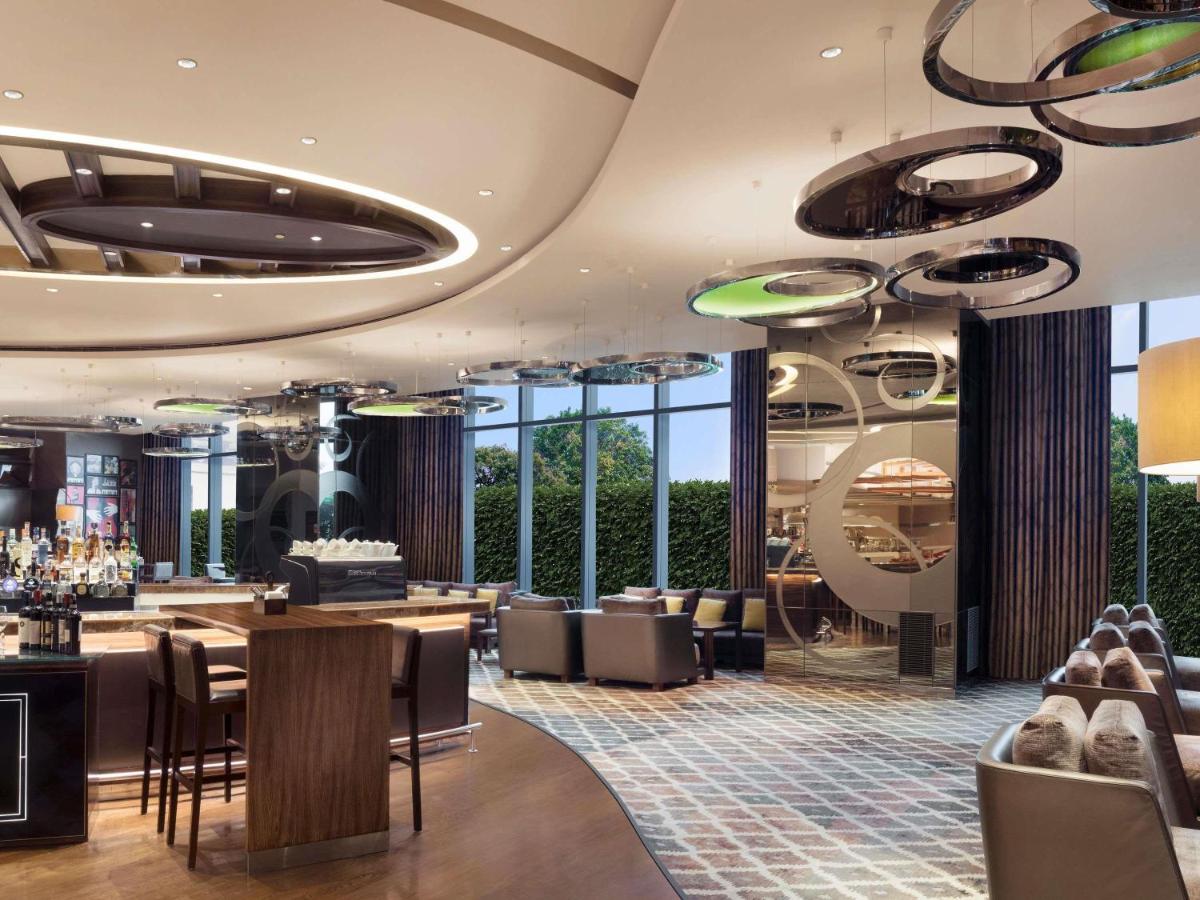 a restaurant with tables and chairs and large windows at Pullman New Delhi Aerocity in New Delhi