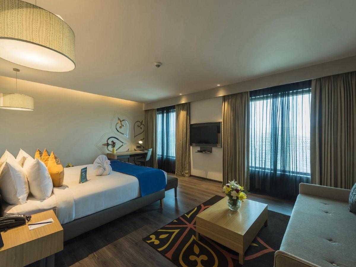 a hotel room with a bed and a couch at Grand Mercure Mysore - An Accor Brand in Mysore