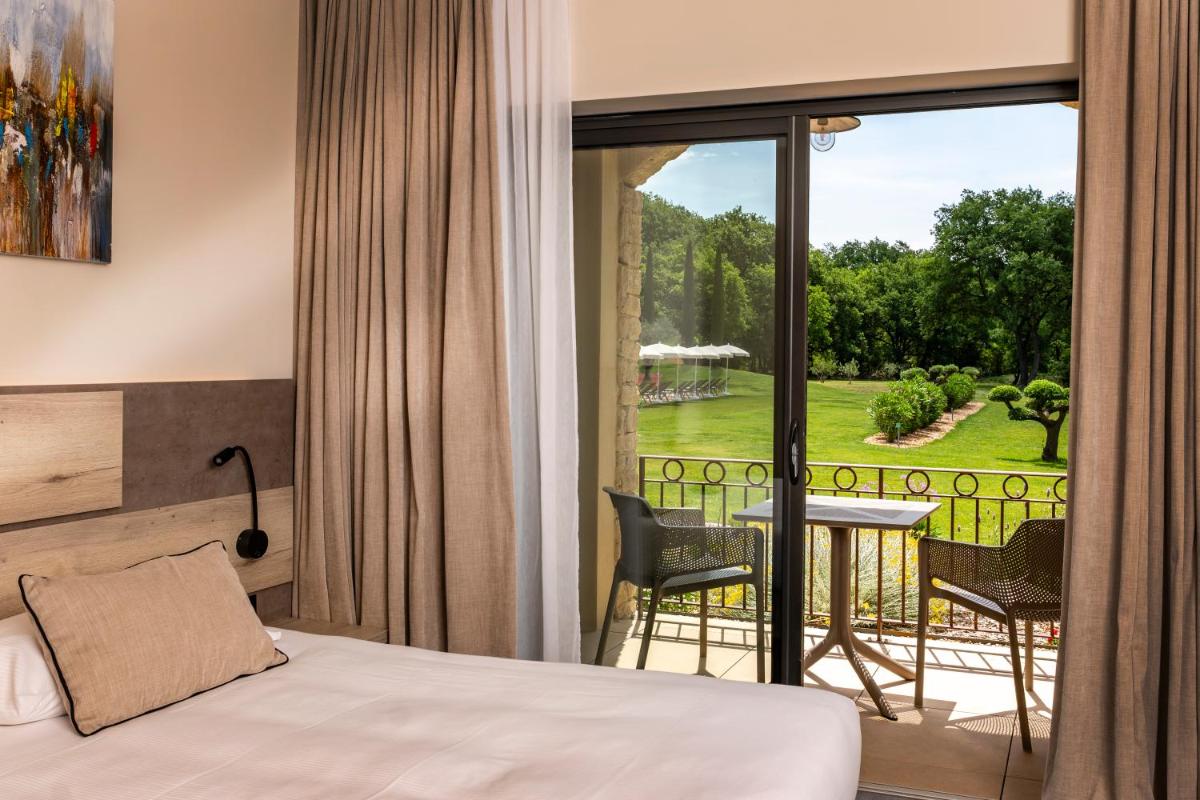 une chambre d'hôtel avec un lit et un balcon dans l'établissement Mas De La Senancole & Spa, à Gordes