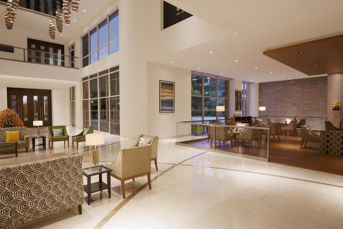 a lobby with tables and chairs in a building at Four Points by Sheraton Hotel and Serviced Apartments Pune in Pune