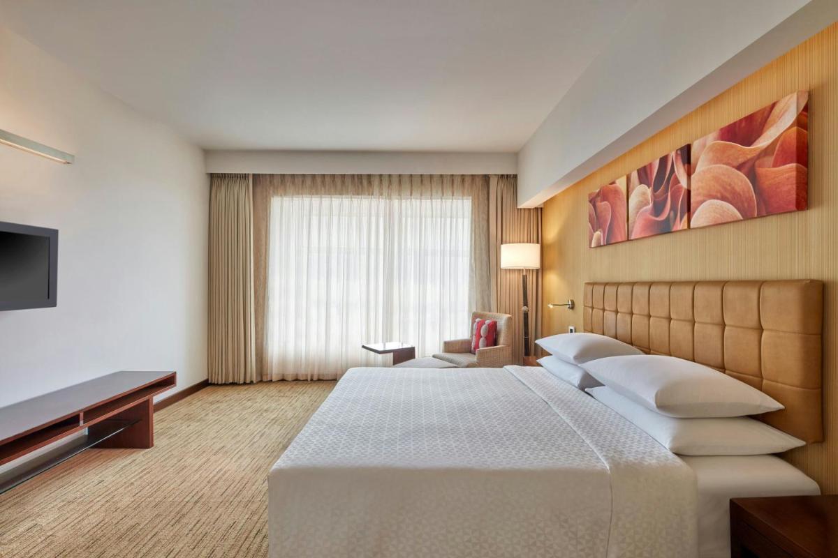 a hotel room with a bed and a flat screen tv at Four Points by Sheraton Hotel and Serviced Apartments Pune in Pune