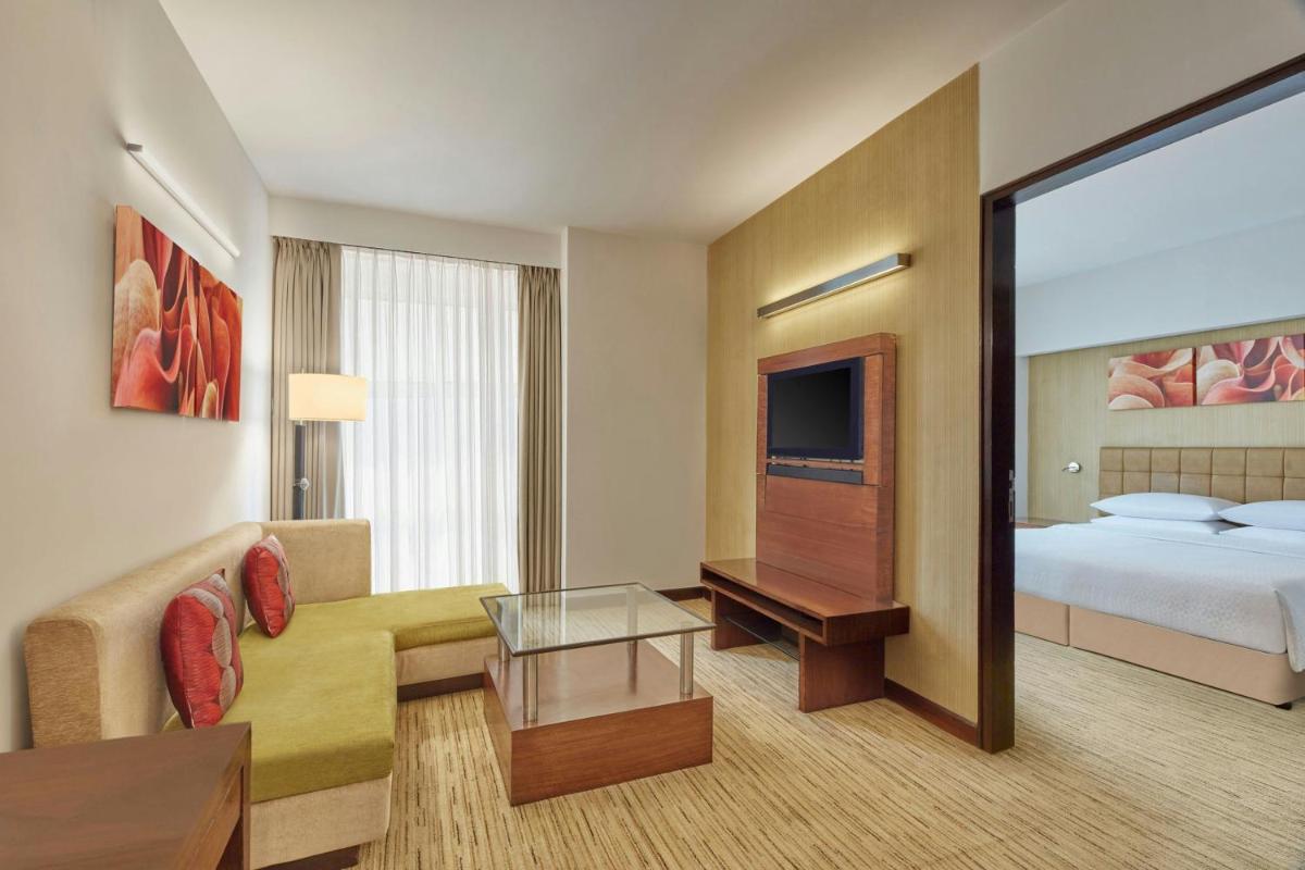 a hotel room with a bed and a living room at Four Points by Sheraton Hotel and Serviced Apartments Pune in Pune