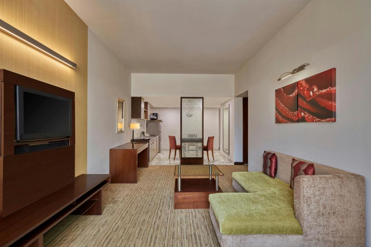 a living room with a couch and a flat screen tv at Four Points by Sheraton Hotel and Serviced Apartments Pune in Pune