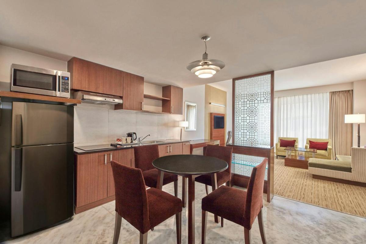a kitchen and living room with a table and chairs at Four Points by Sheraton Hotel and Serviced Apartments Pune in Pune