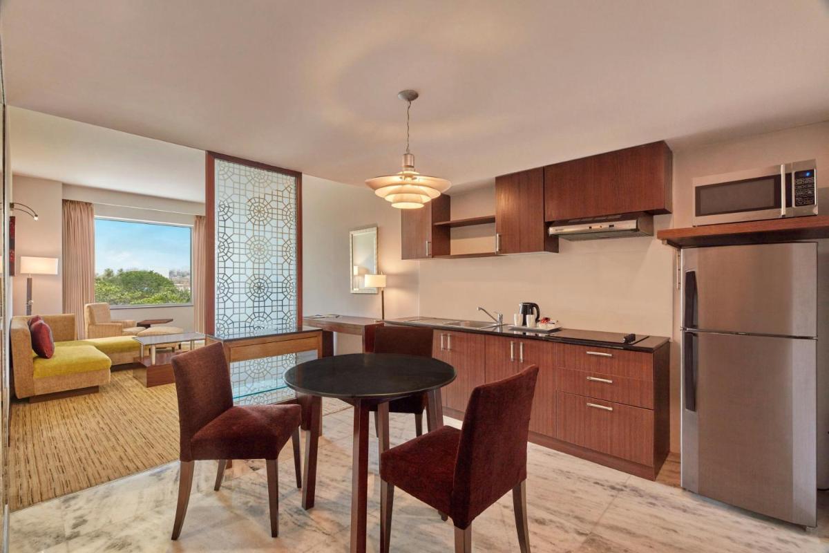 a kitchen and living room with a table and chairs at Four Points by Sheraton Hotel and Serviced Apartments Pune in Pune