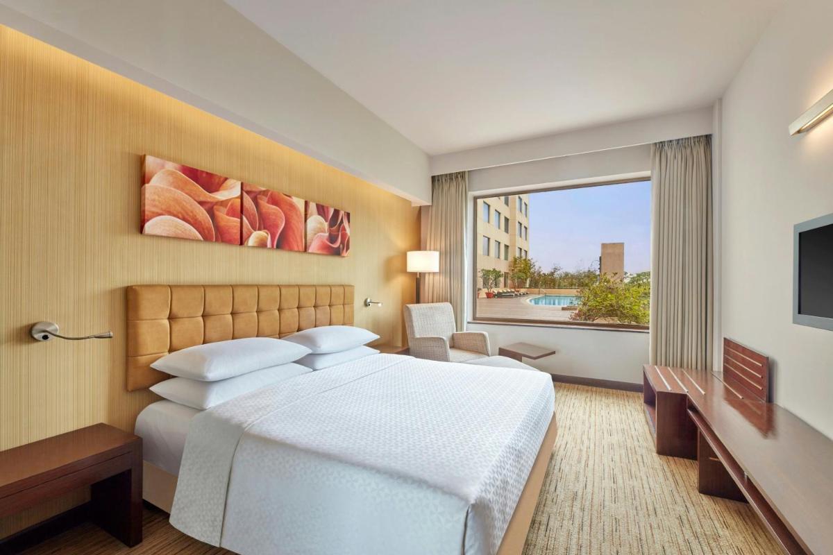 a bedroom with a white bed and a large window at Four Points by Sheraton Hotel and Serviced Apartments Pune in Pune