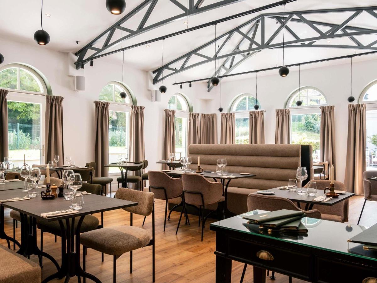 un restaurant avec des tables, des chaises et des fenêtres dans l'établissement Mercure Maintenon, à Maintenon