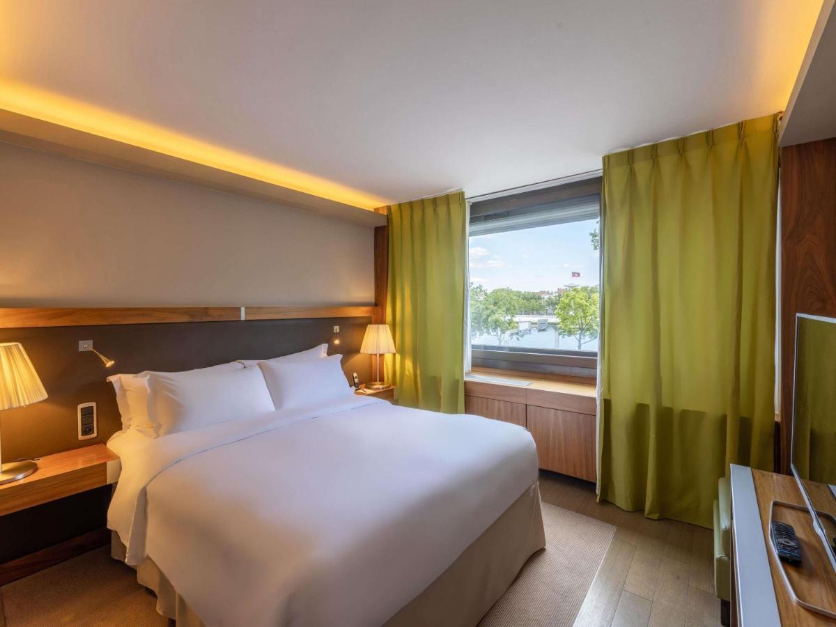 une chambre avec un grand lit blanc et une fenêtre dans l'établissement Sofitel Lyon Bellecour, à Lyon