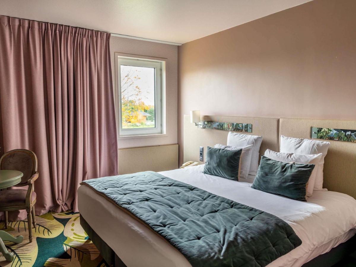 une chambre avec un grand lit et une fenêtre dans l'établissement Hotel Mercure Parc du Coudray - Barbizon, à Le Coudray-Montceaux