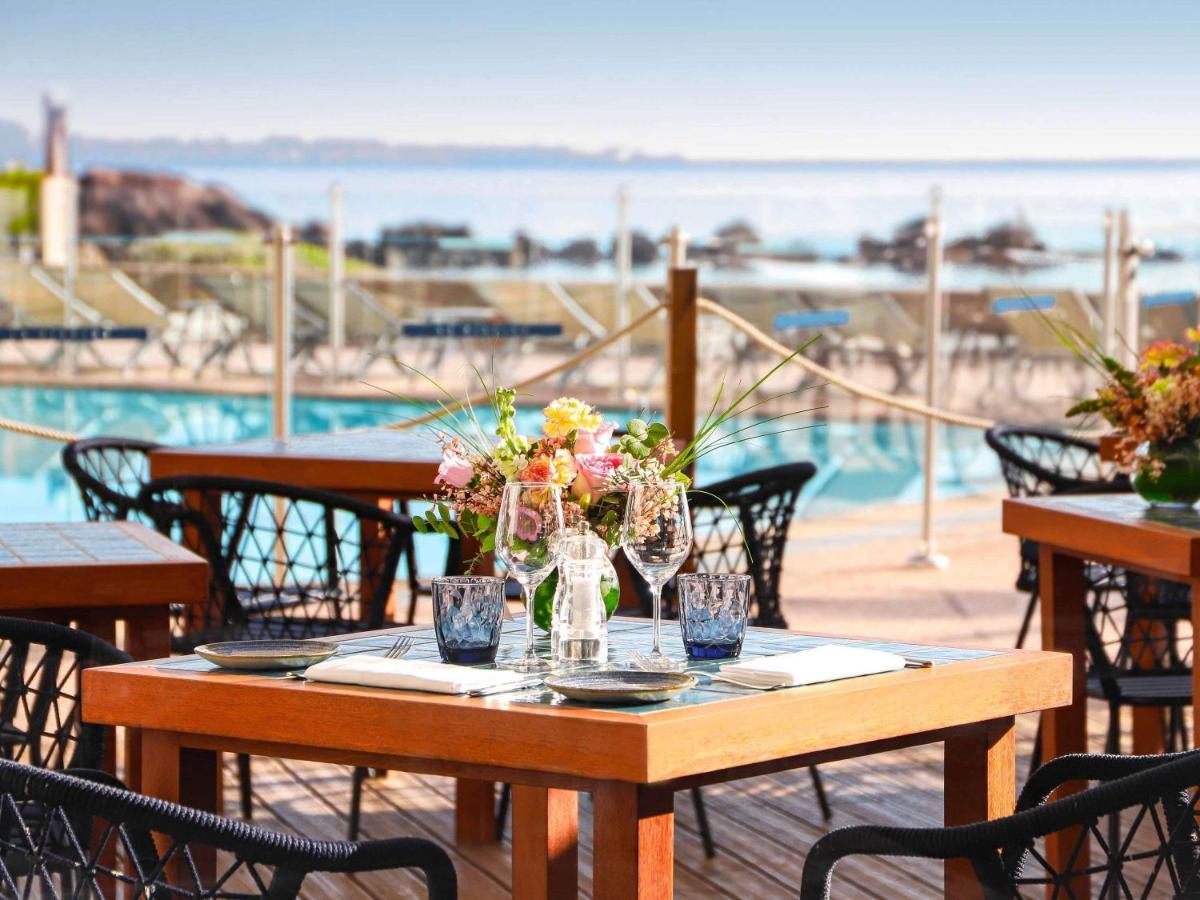une table en bois avec des fleurs dessus à côté d'une piscine dans l'établissement Pullman Cannes Mandelieu, à Mandelieu-la-Napoule