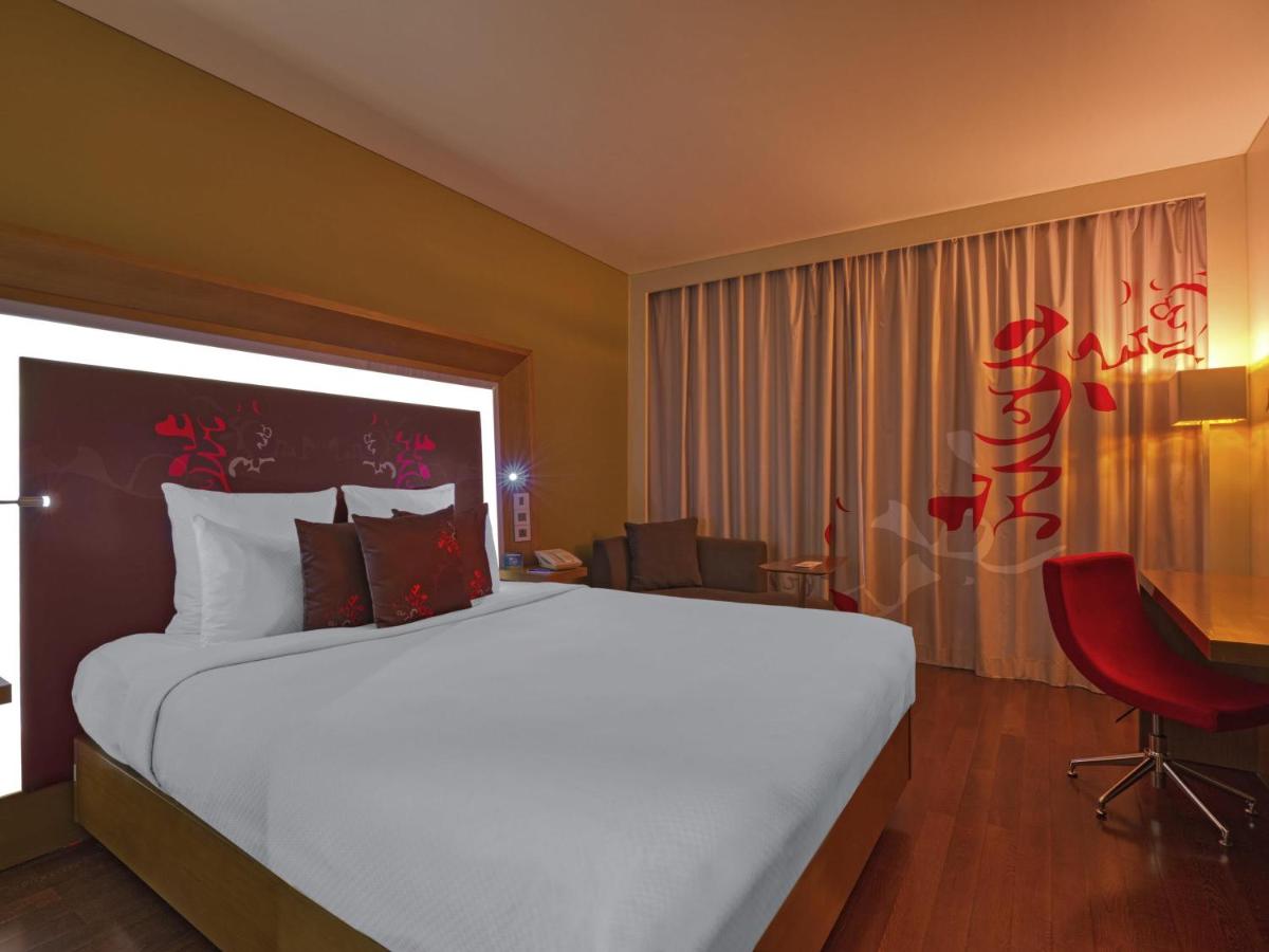 a hotel room with a large bed and a desk at Novotel Bengaluru Outer Ring Road in Bengaluru