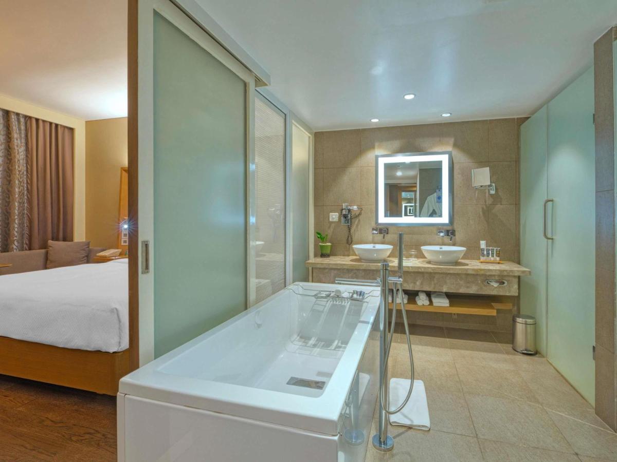 a bathroom with two sinks and a bed in a room at Novotel Bengaluru Outer Ring Road in Bengaluru