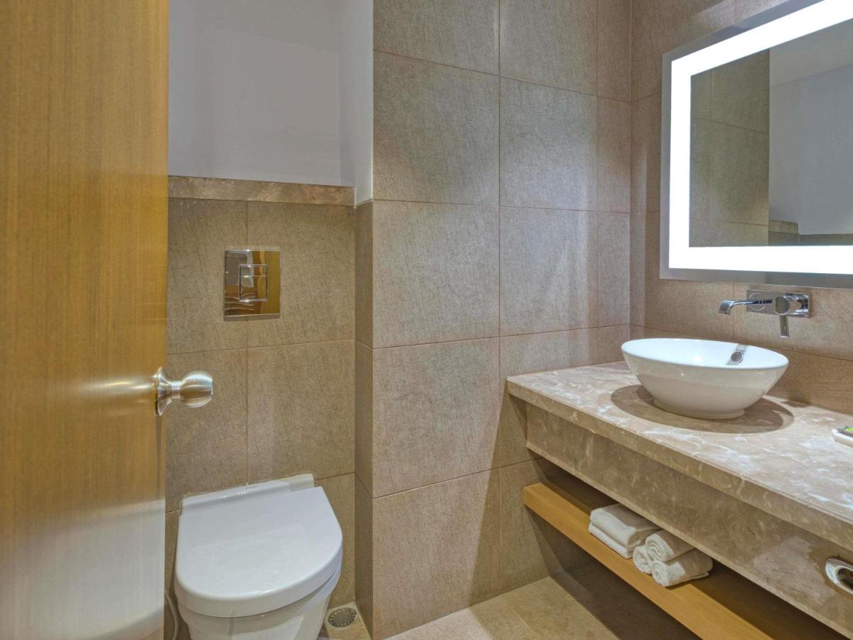 a bathroom with a toilet and a sink at Novotel Bengaluru Outer Ring Road in Bengaluru