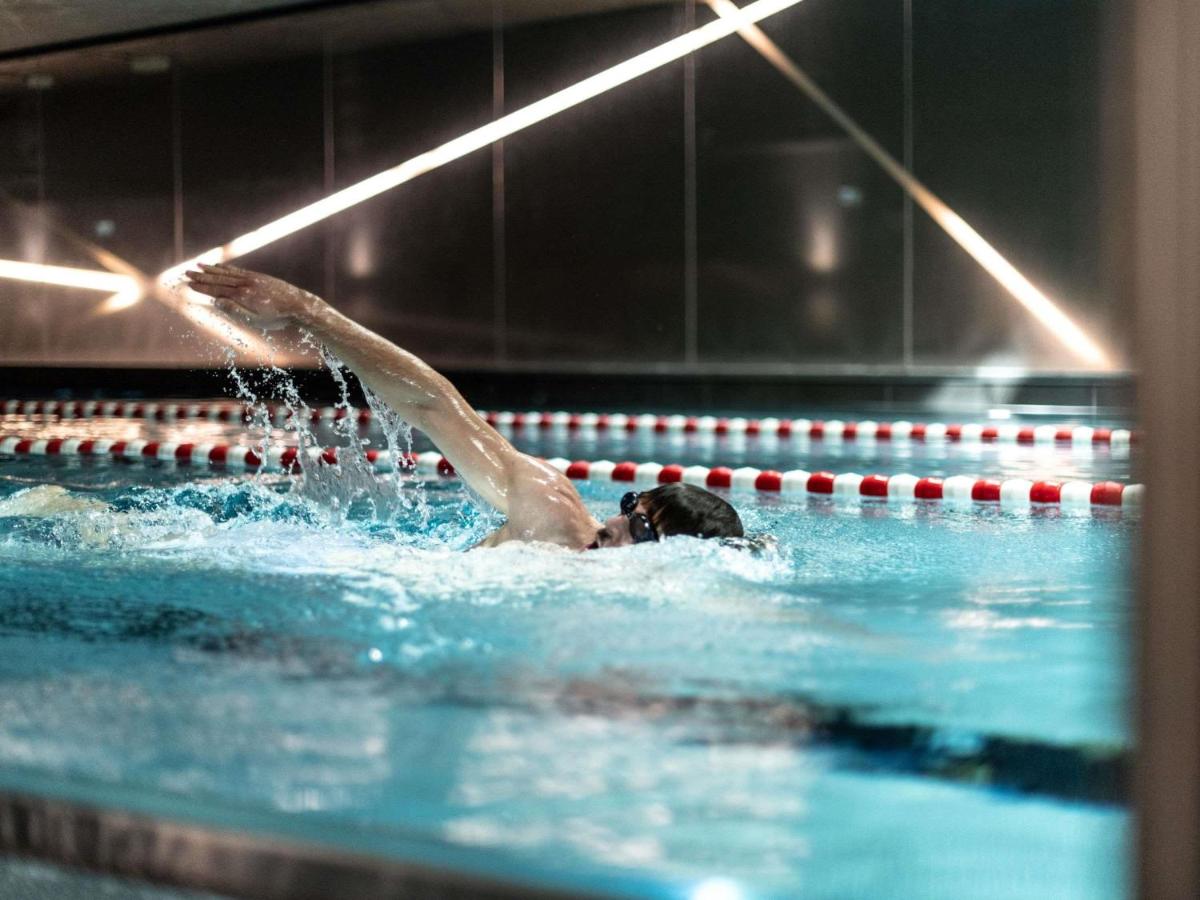 Eine Frau schwimmt in einem Schwimmbecken in einem Fitnessstudio in der Unterkunft Sofitel Frankfurt Opera in Frankfurt am Main