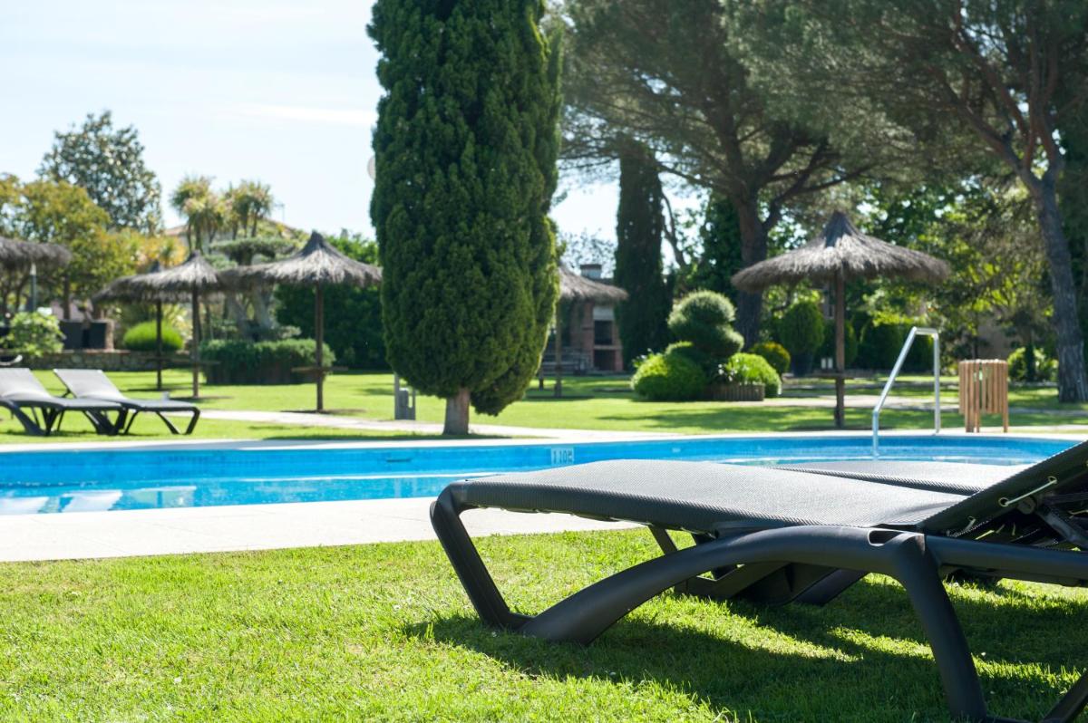 una piscina con una mesa de picnic y sombrillas en Hotel Mas Solà, en Santa Coloma de Farners