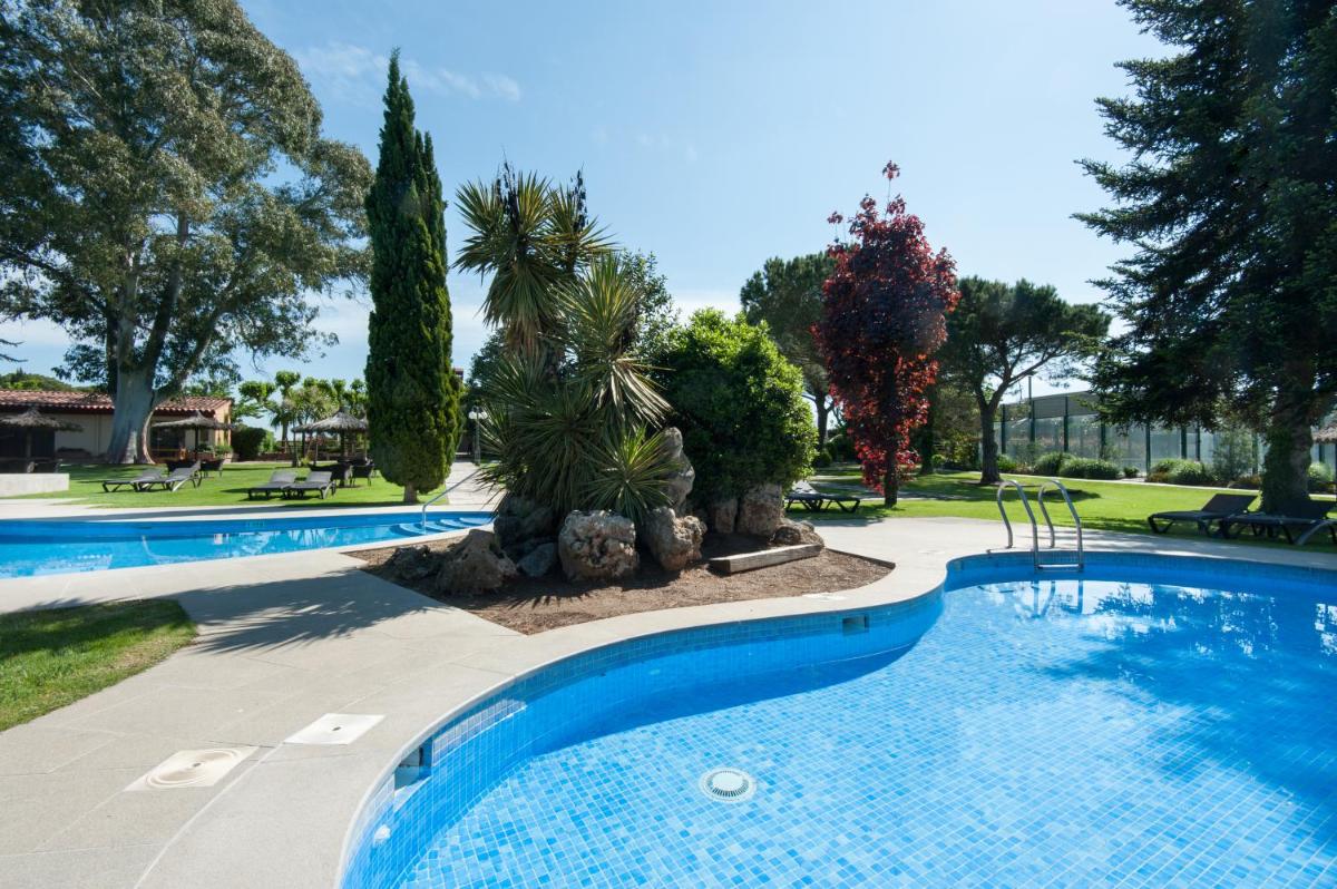 una piscina en un complejo con árboles en Hotel Mas Solà, en Santa Coloma de Farners