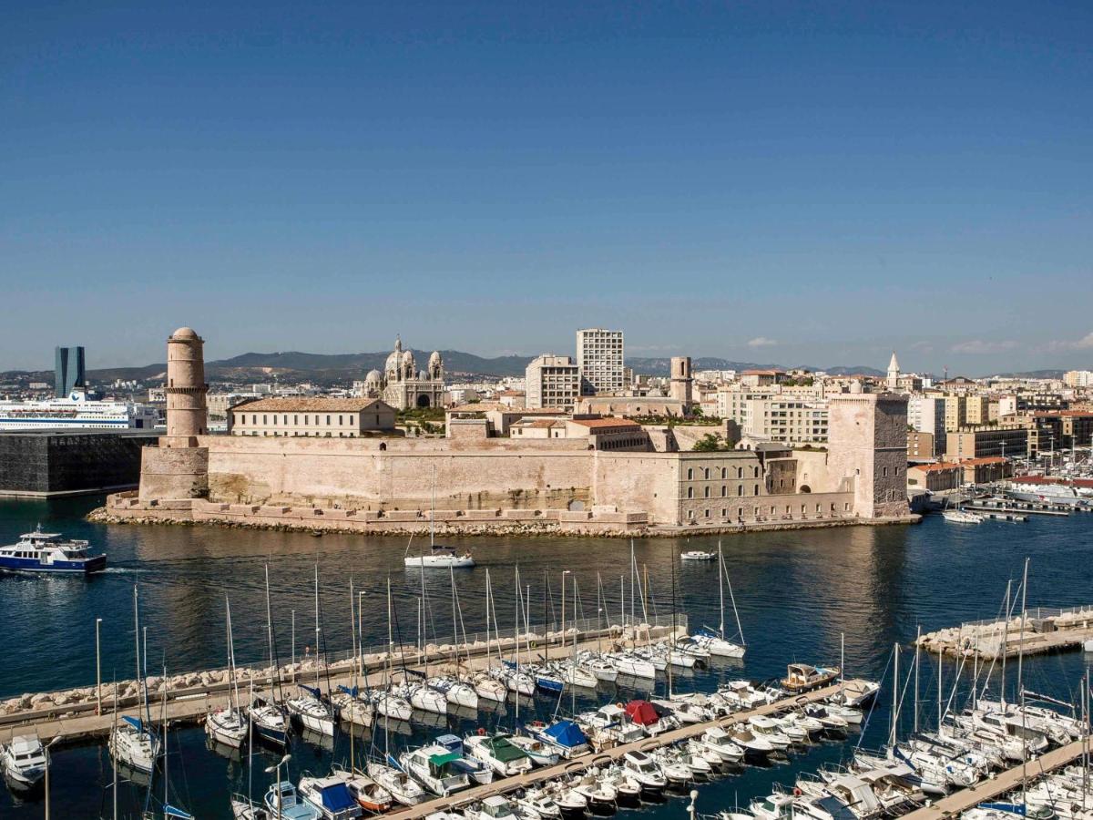une ville avec des bateaux amarrés dans un port dans l'établissement Sofitel Marseille Vieux-Port, à Marseille