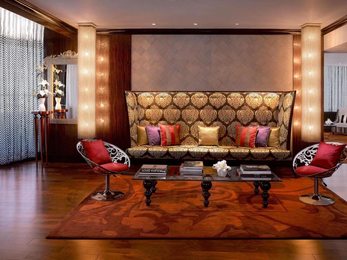 a living room with a couch and two red chairs at Sofitel Mumbai BKC in Mumbai