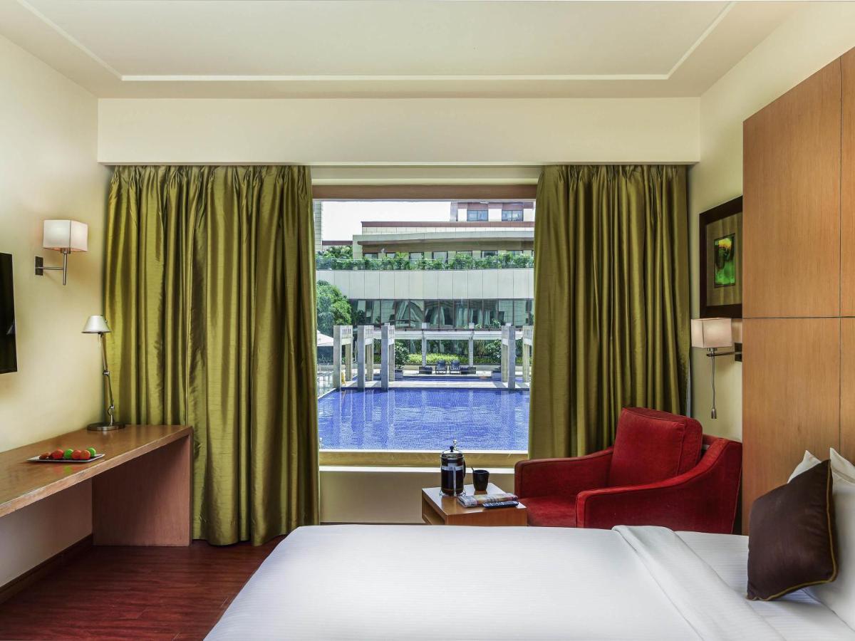 a hotel room with a bed and a window at Novotel Hyderabad Airport in Hyderabad