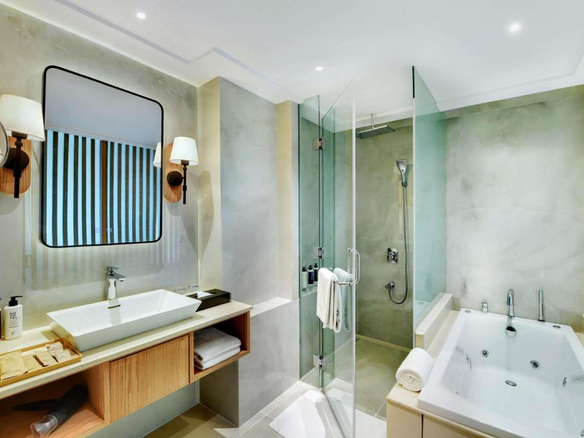 a bathroom with a tub and a sink and a shower at Novotel Hyderabad Airport in Hyderabad