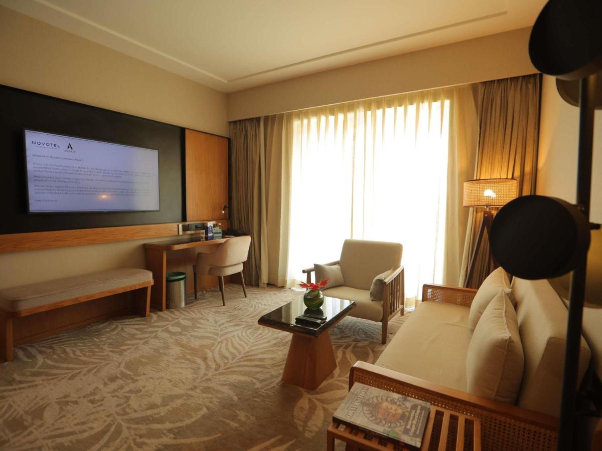 a hotel room with a couch and a desk at Novotel Hyderabad Airport in Hyderabad