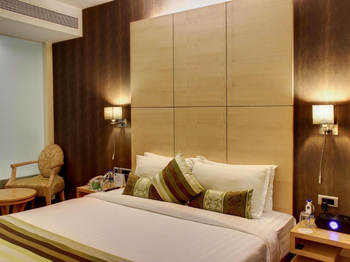 a hotel room with a bed and a chair at Novotel Hyderabad Airport in Hyderabad