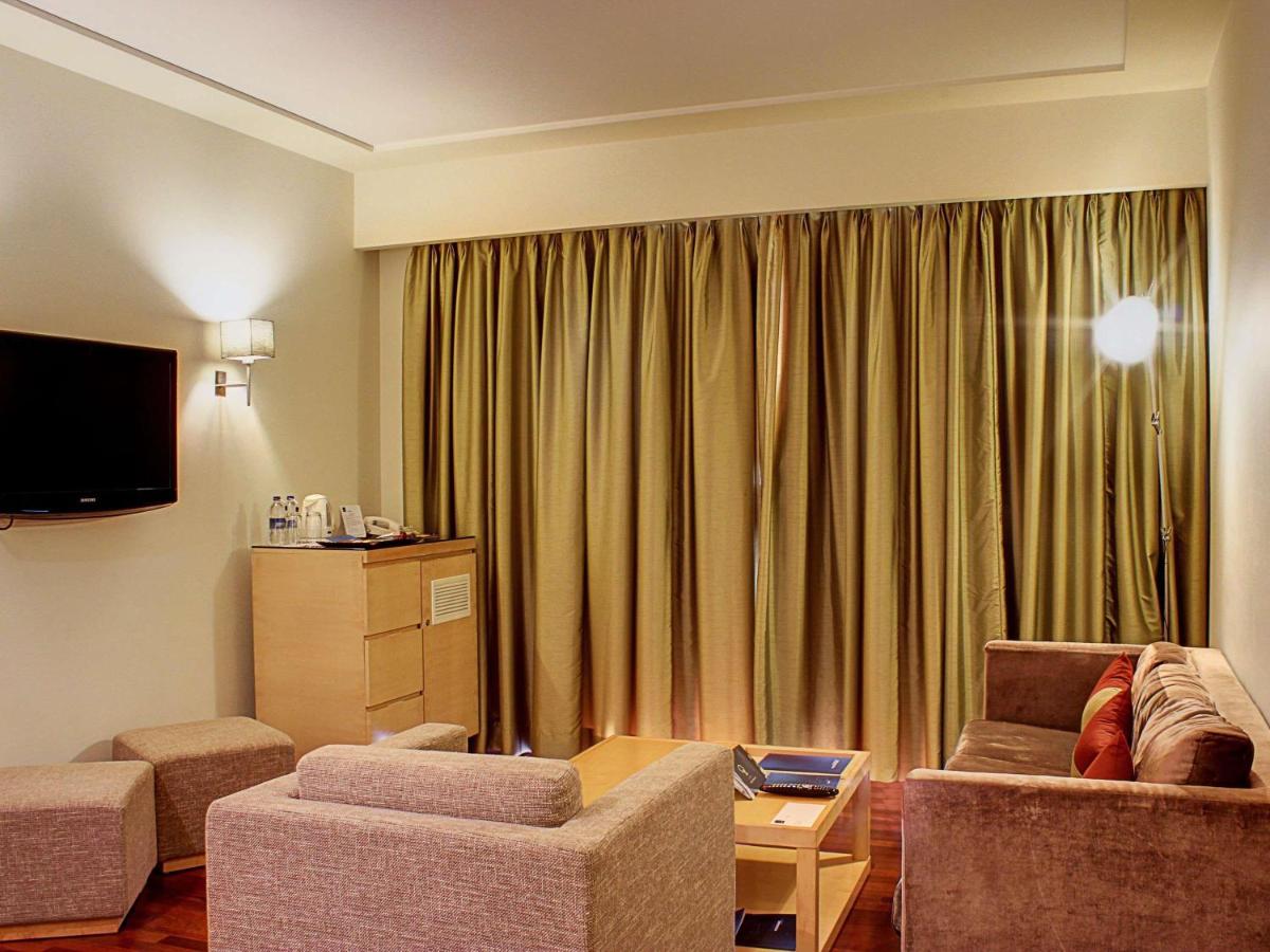a living room with a couch and a tv and curtains at Novotel Hyderabad Airport in Hyderabad