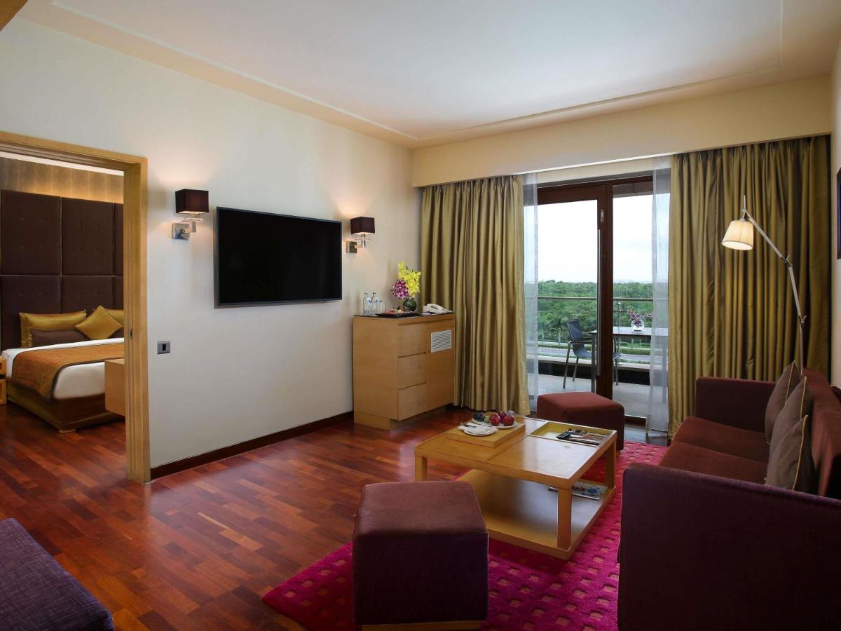 a hotel room with a living room with a television at Novotel Hyderabad Airport in Hyderabad