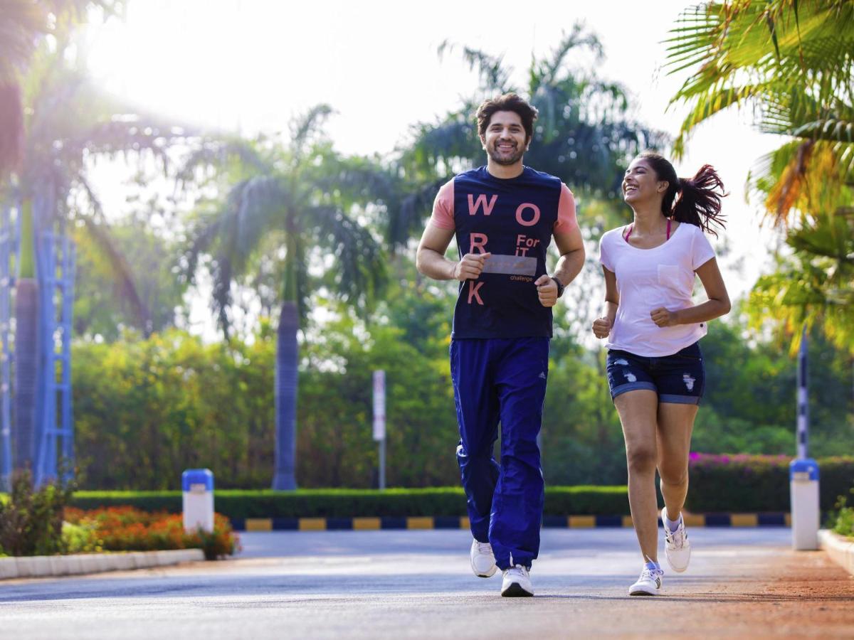a man and a woman running in a park at Novotel Hyderabad Airport in Hyderabad