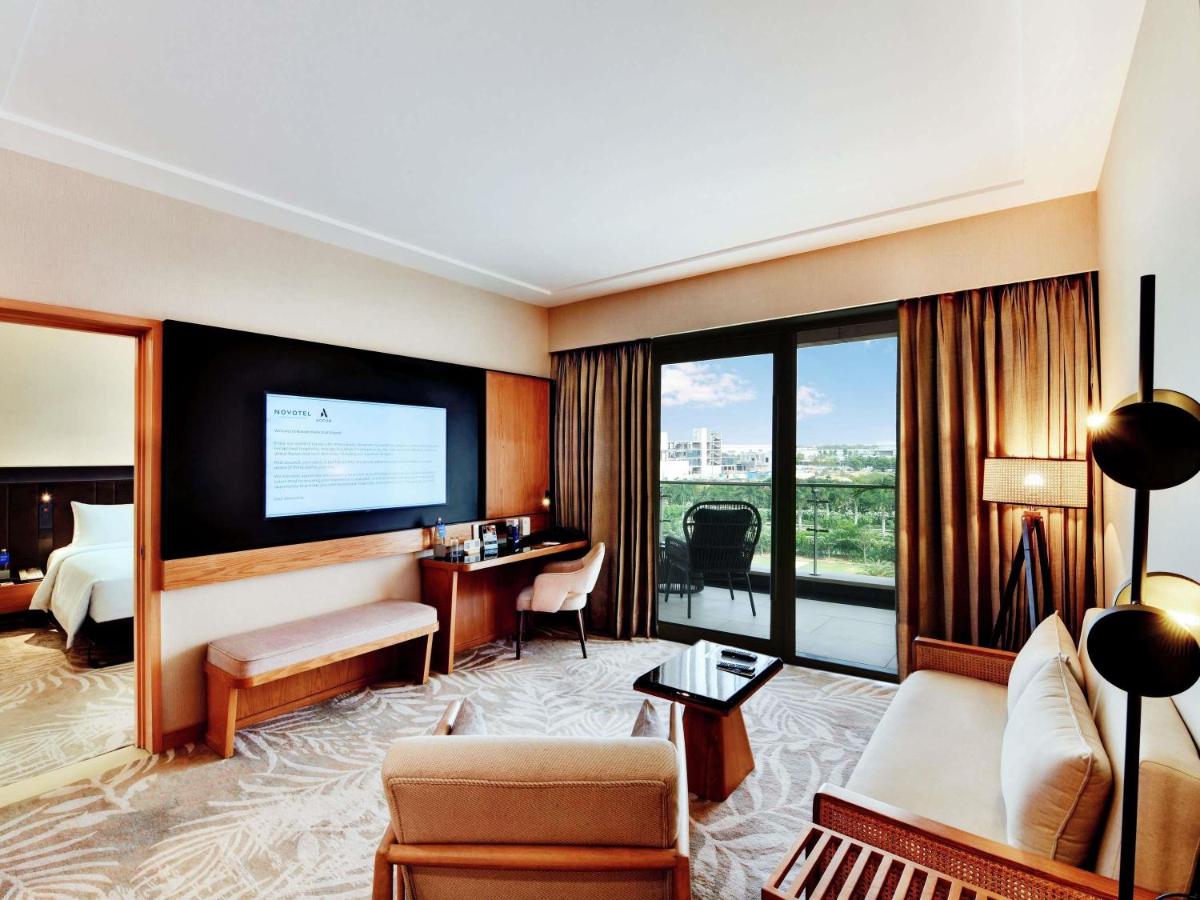 a hotel room with a television and a living room at Novotel Hyderabad Airport in Hyderabad