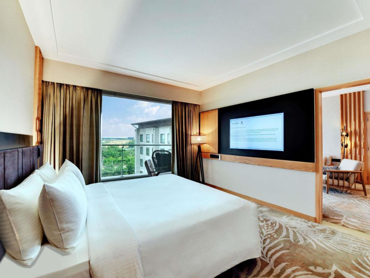 a hotel room with a large bed and a large window at Novotel Hyderabad Airport in Hyderabad