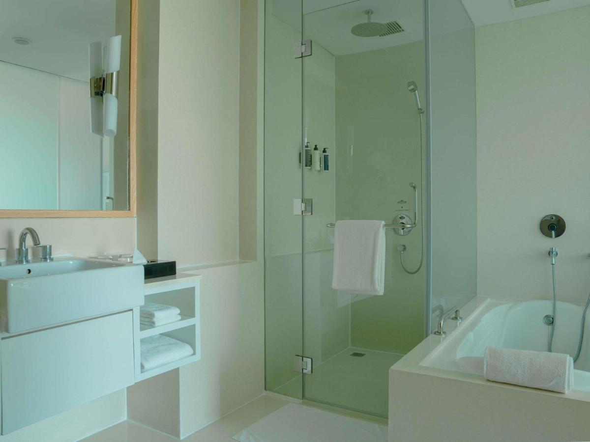 a white bathroom with a shower and a sink at Novotel Hyderabad Airport in Hyderabad