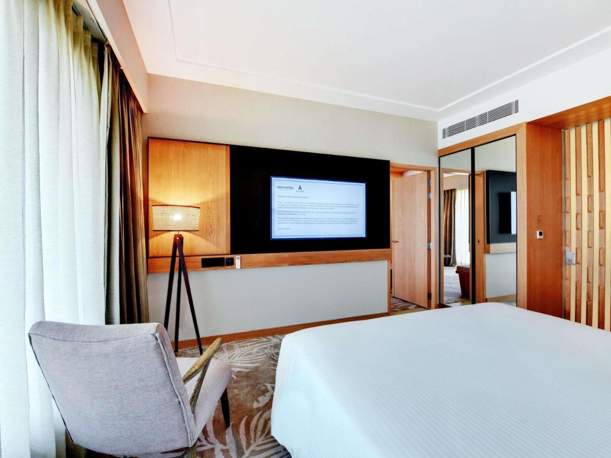 a hotel room with a bed and a television at Novotel Hyderabad Airport in Hyderabad