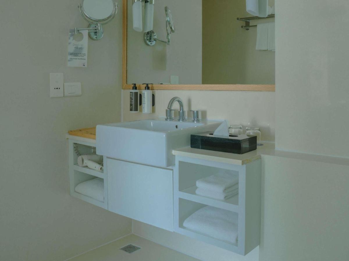 a white bathroom with a sink and a mirror at Novotel Hyderabad Airport in Hyderabad
