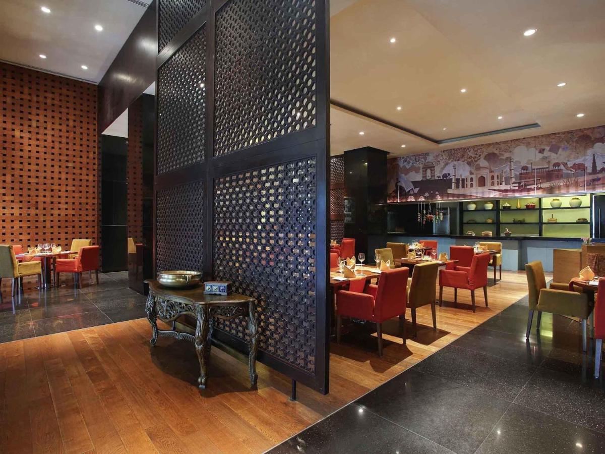 a dining room with tables and chairs in a restaurant at Novotel Hyderabad Airport in Hyderabad
