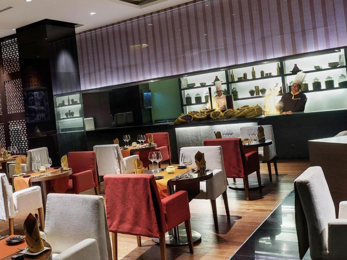 a restaurant with tables and chairs and a person in the background at Novotel Hyderabad Airport in Hyderabad