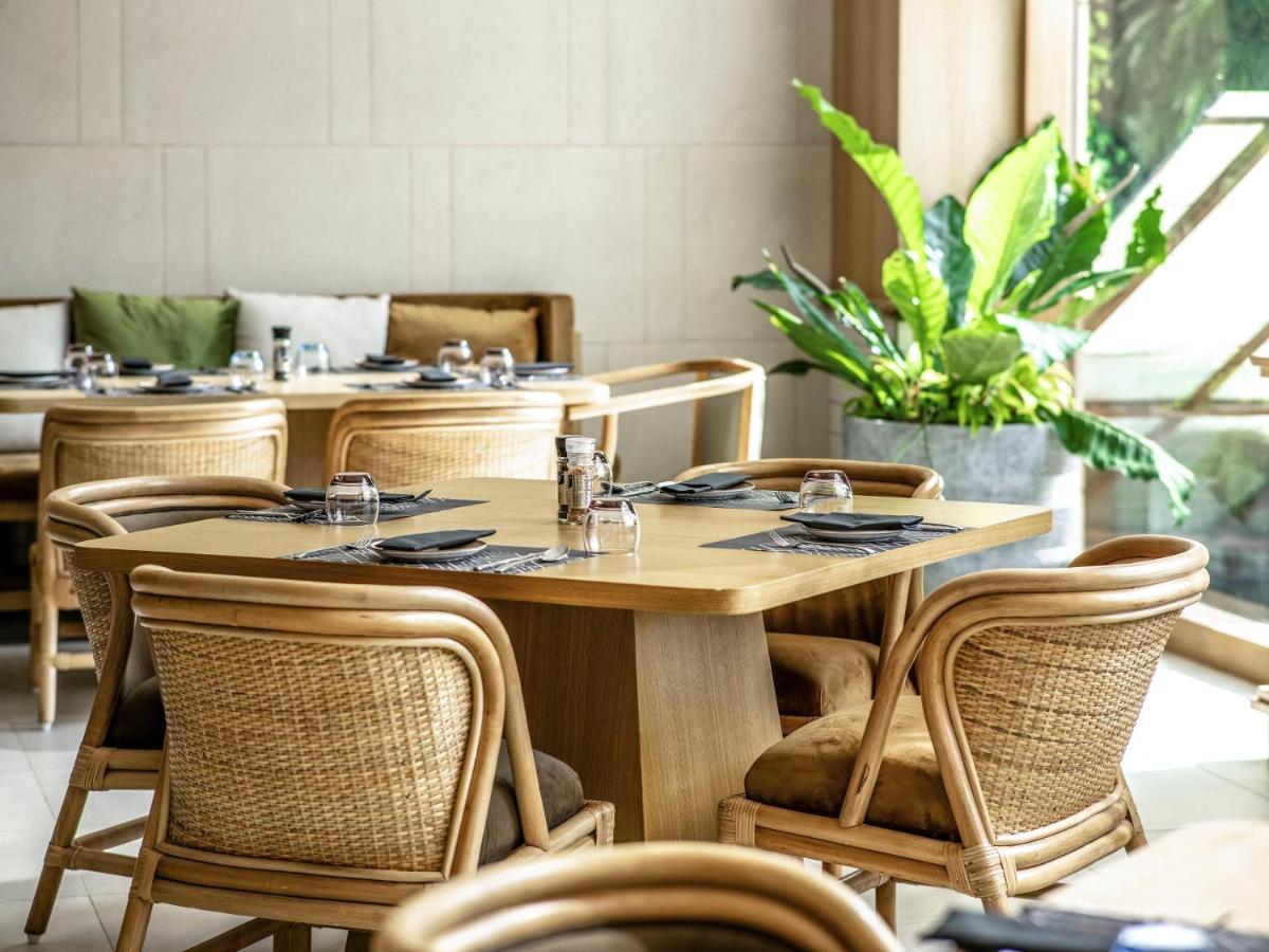 a dining room with tables and rattan chairs at Novotel Hyderabad Airport in Hyderabad