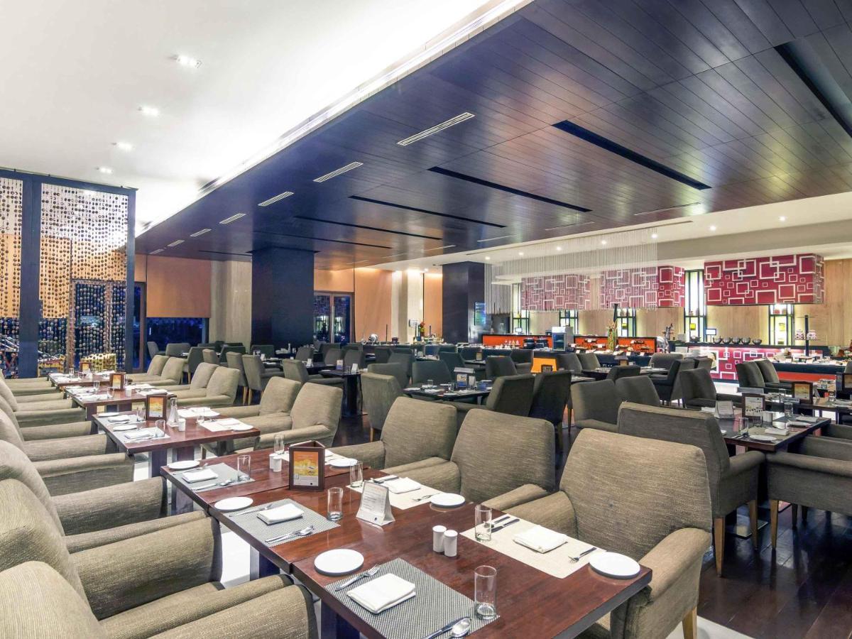 a restaurant with tables and chairs in a room at Novotel Hyderabad Airport in Hyderabad