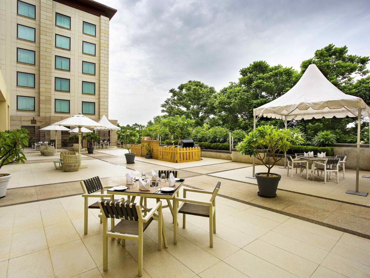 a patio with tables and chairs and umbrellas at Novotel Hyderabad Airport in Hyderabad