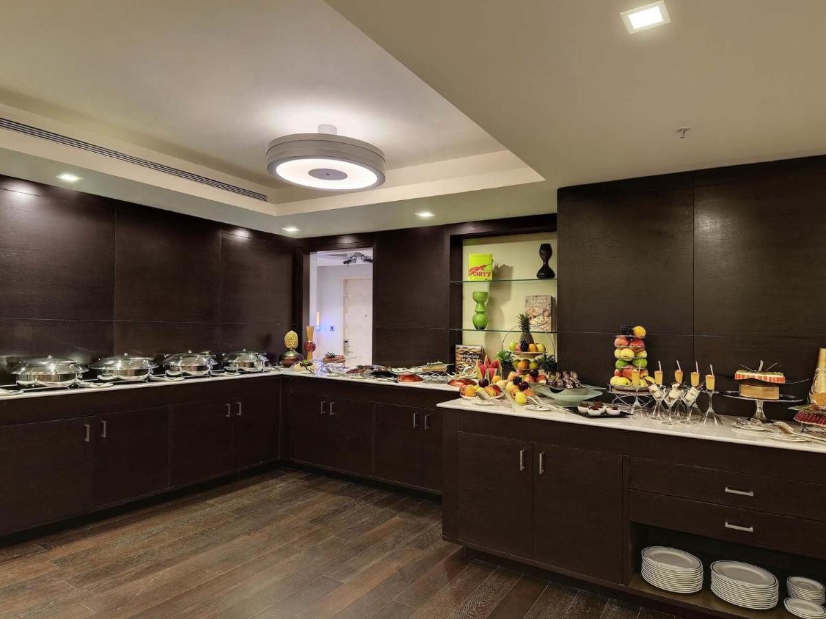 a large kitchen with brown cabinets and a large counter top at Novotel Hyderabad Airport in Hyderabad