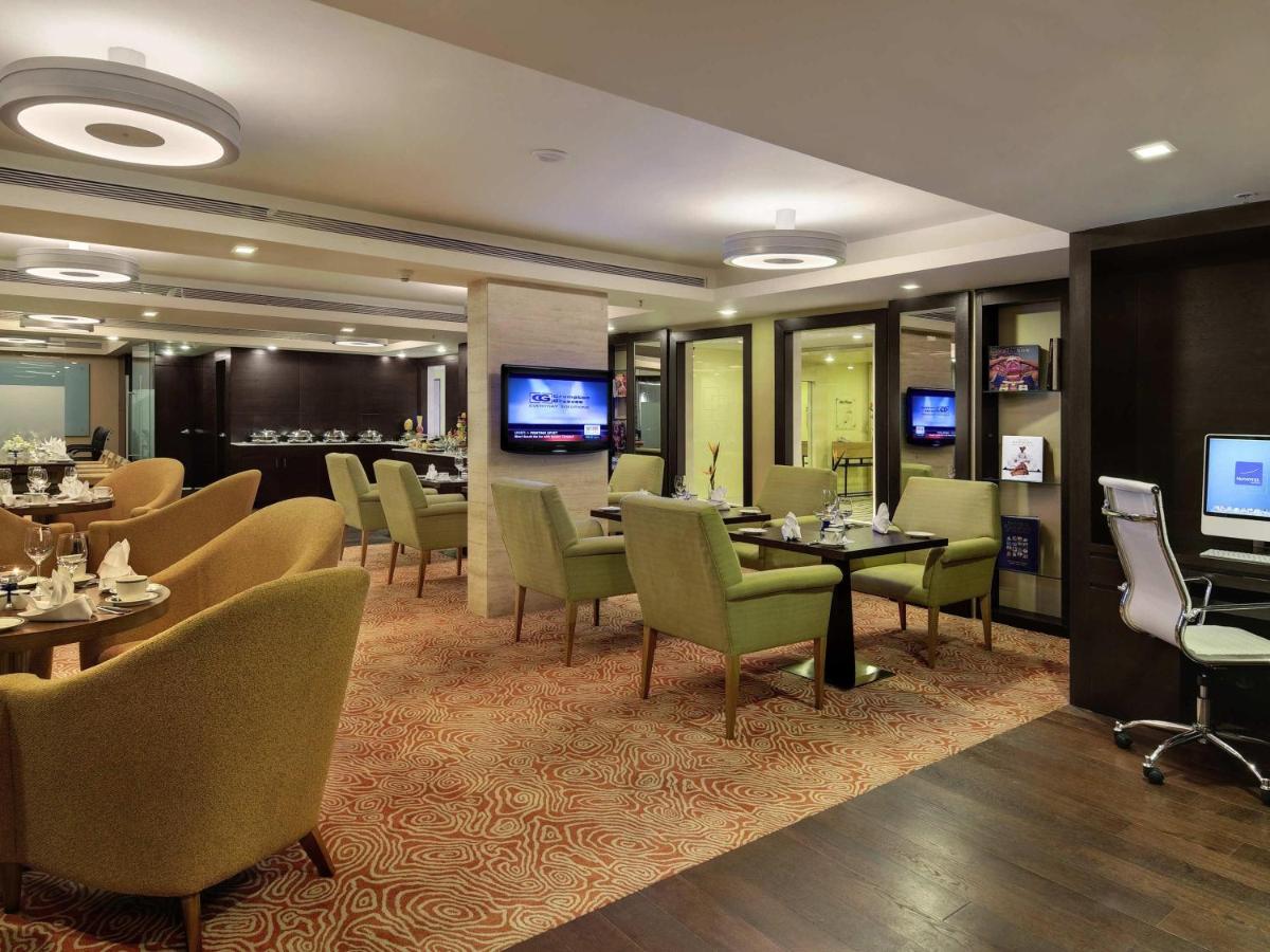 a restaurant with tables and chairs and a bar at Novotel Hyderabad Airport in Hyderabad