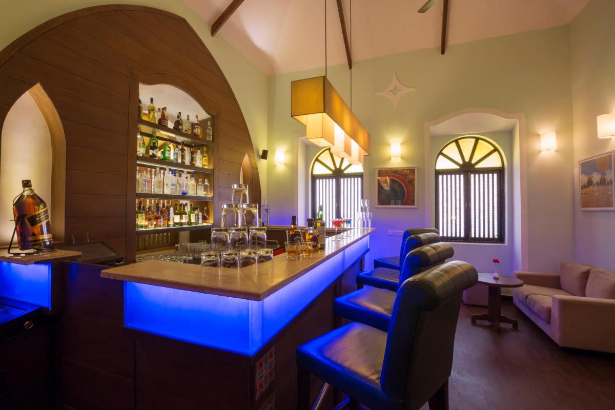 a bar in a room with blue lighting at Deltin Suites in Candolim