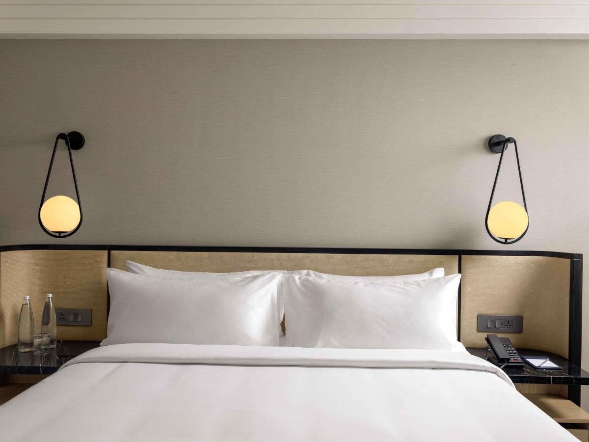 a large bed with two lights above it at Pullman Chennai Anna Salai - Premium Brand By Accor in Chennai