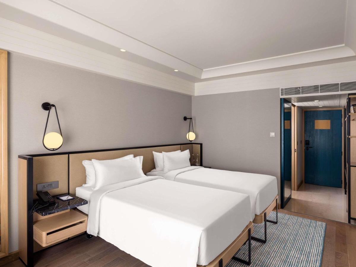 a hotel room with two beds and a mirror at Pullman Chennai Anna Salai - Premium Brand By Accor in Chennai