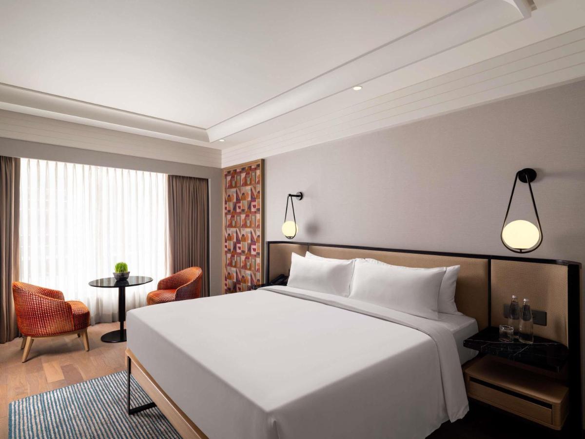 a bedroom with a large white bed and a table at Pullman Chennai Anna Salai - Premium Brand By Accor in Chennai