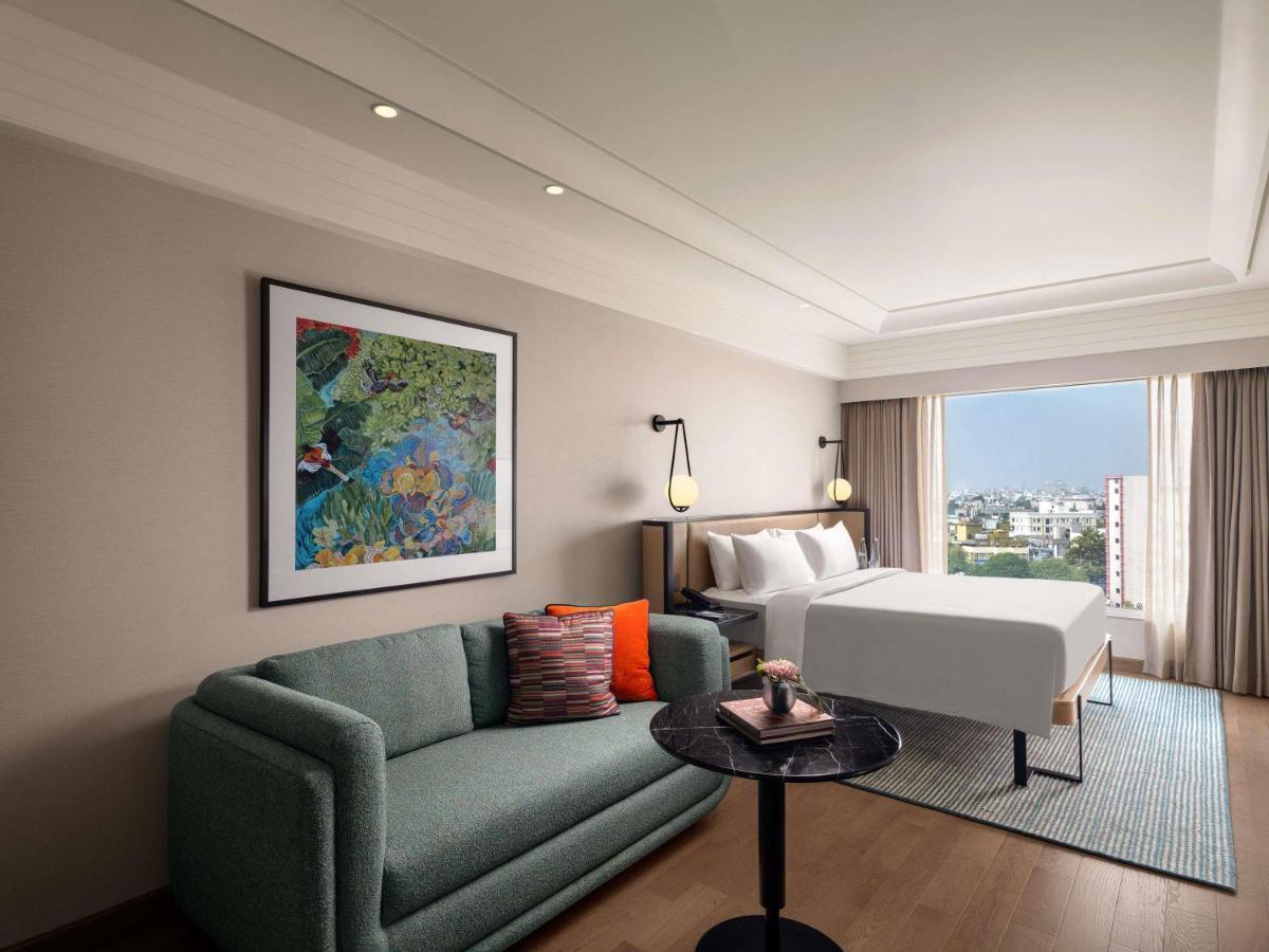 a hotel room with a couch and a bed at Pullman Chennai Anna Salai - Premium Brand By Accor in Chennai