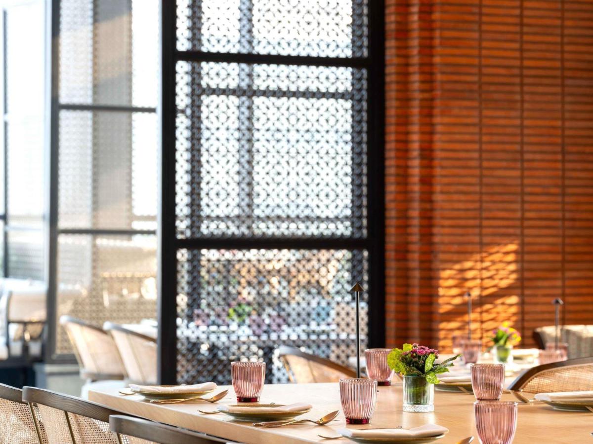 a table in a restaurant with chairs and a fireplace at Pullman Chennai Anna Salai - Premium Brand By Accor in Chennai