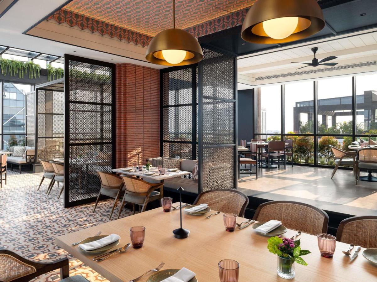 a restaurant with tables and chairs and windows at Pullman Chennai Anna Salai - Premium Brand By Accor in Chennai