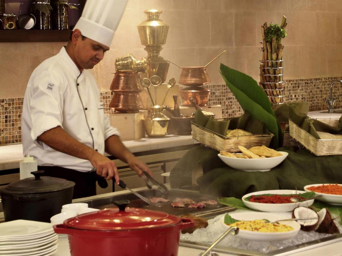 a chef is preparing food in a kitchen at Novotel Mumbai Juhu Beach in Mumbai
